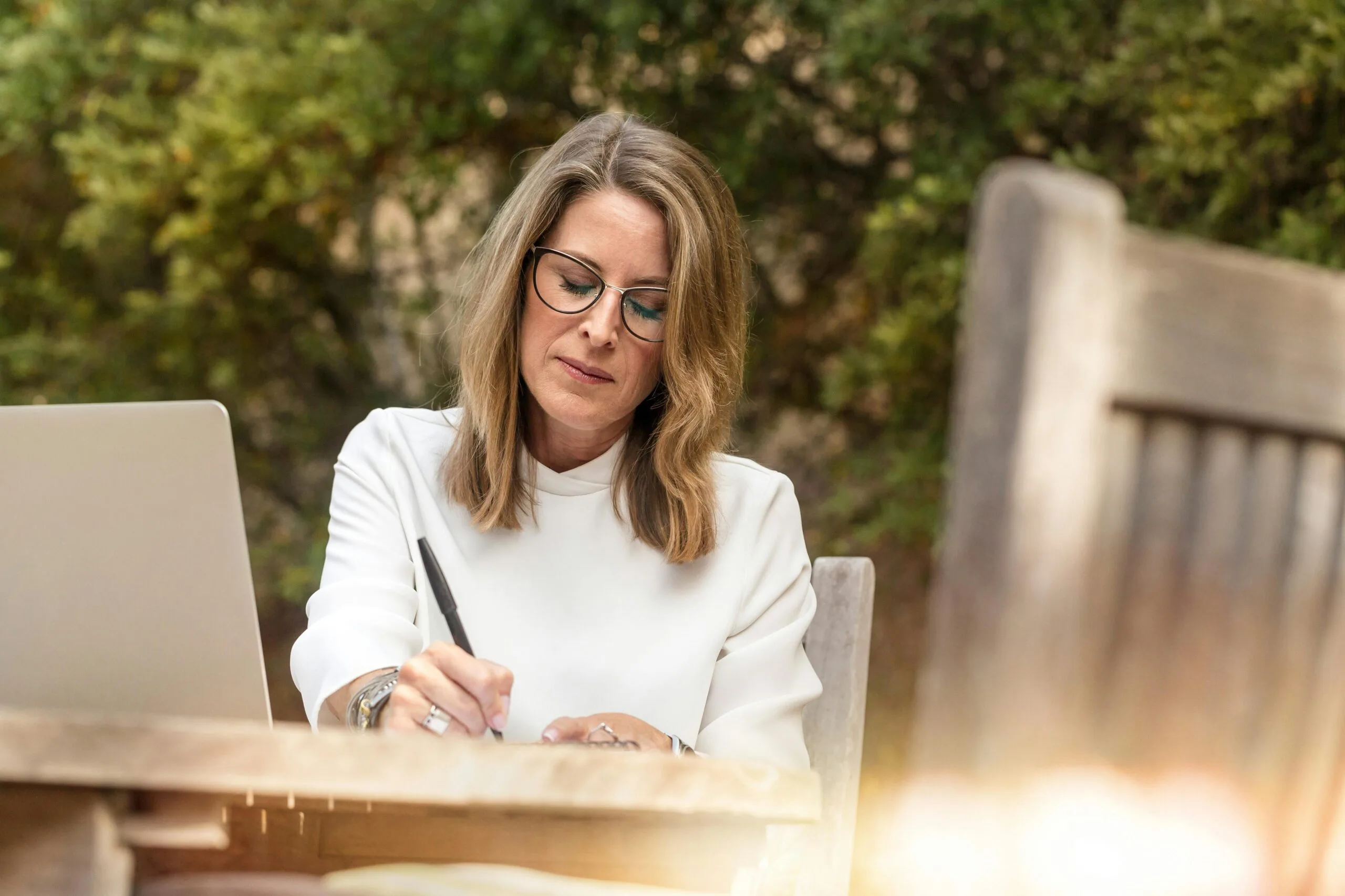 A woman writing in a journal at a table outside